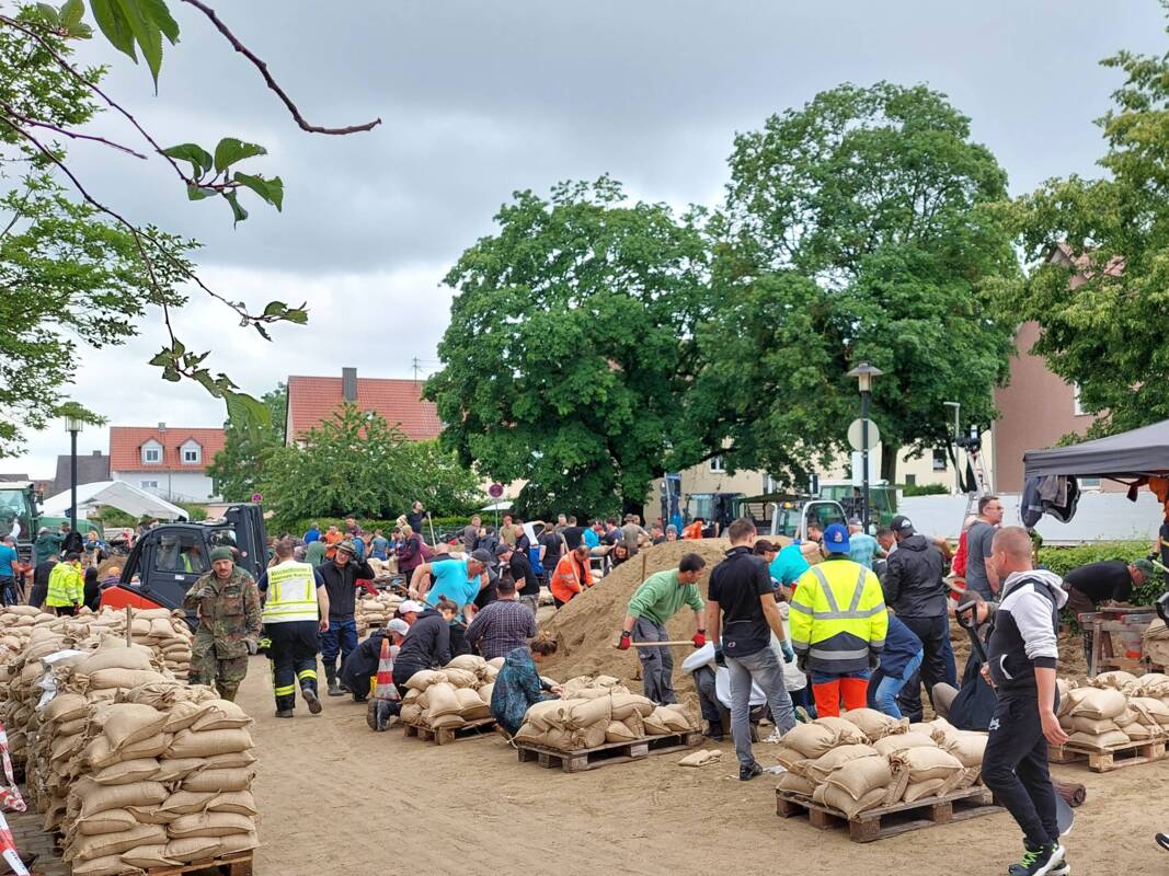 Helfer füllen am Feuerwehrhaus Manching beim Hochwasser 2024 Sandsäcke